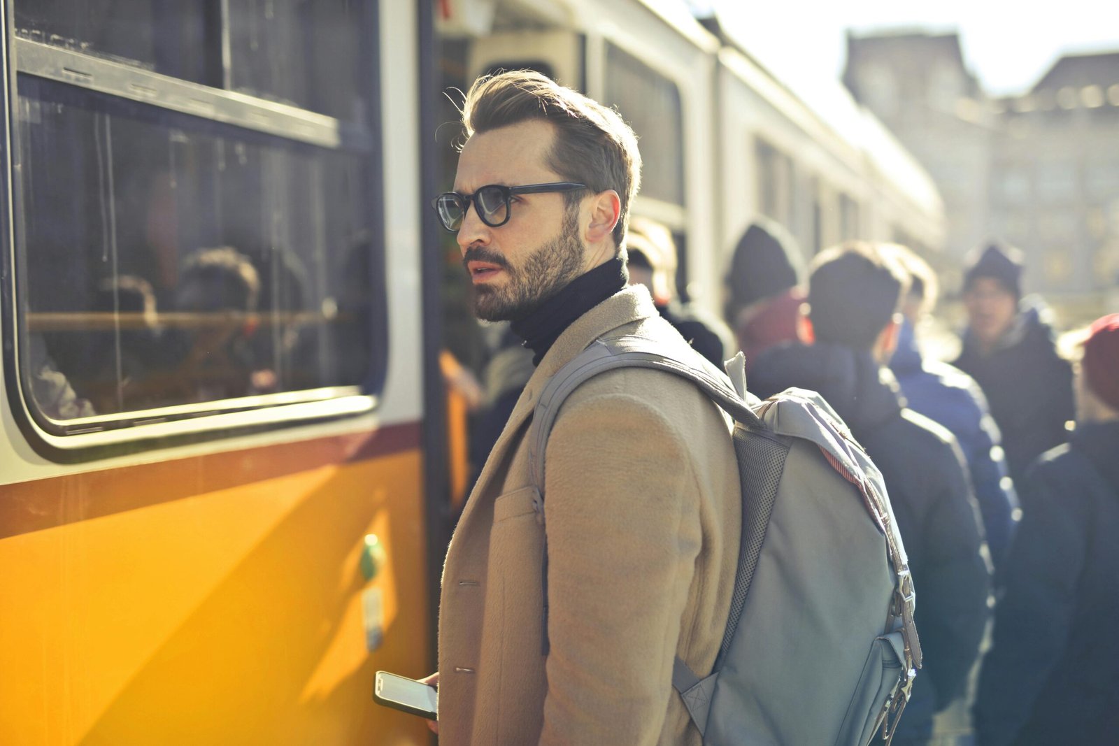 Mercado de estética masculina é promissor para investir em 2025 1 A stylish man with a backpack boards a tram in bustling Budapest, Hungary, during the day.